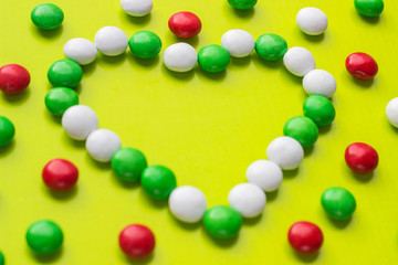 Candies in the shape of heart on yellow background