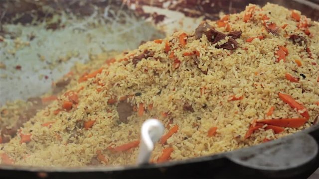 Pilaf (Plov) preparation Afghan, Uzbek Tajik national cuisine main dish large cast-iron cauldron on fire mixed ready pilaf sliced red carrot barberry garlic red chili pepper rice lamb mutton fat oil 