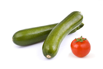 Two green zucchini and a cherry tomato, isolated on white background. Still-life picture taken in studio with soft-box.