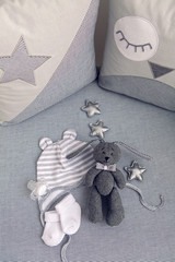 round white baby bed with gray pillows and plush rabbit