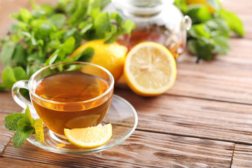 Cup of tea with mint and lemon on brown wooden table
