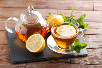 Cup of tea with mint and lemon on brown wooden table
