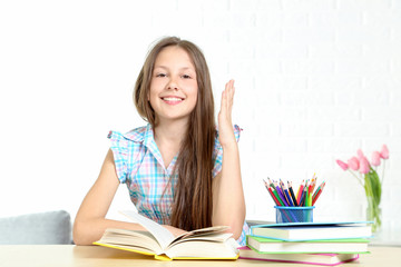 Young girl sitting at the desk and reading book