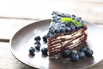 Tasty piece of cake with blueberries on wooden table