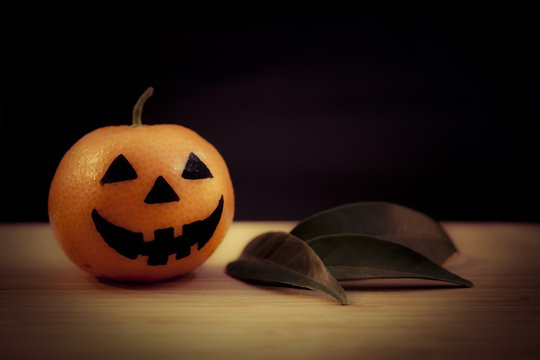 Tangerine - Halloween pumpkin with leaves on a dark background. Still life picture taken in studio.