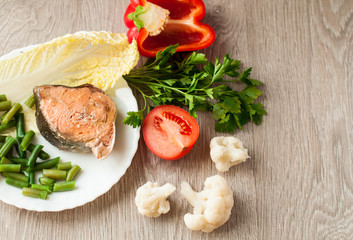 The concept of dietetic foods, fish and vegetables. On a wooden background