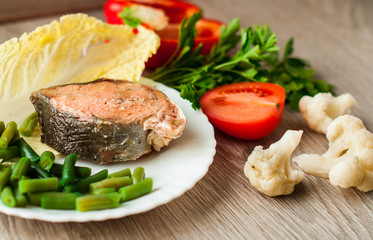 Seafood, red fish with vegetables. On a wooden background.