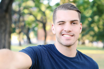 Young latin man taking a selfie in a park.