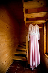 Fototapeta na wymiar Closeup of the wedding dress hanging at wooden stairs