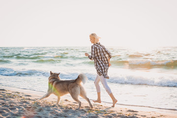 Young female running with siberian husky dog on the beach at sunrise © sashafolly