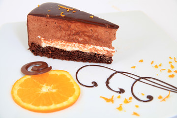 Piece of chocolate cake with decoration on white plate