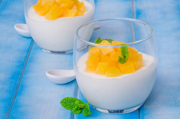 Bavarian cream mousse with vanilla and peaches in syrup in a glass
