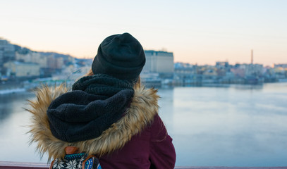 Girl traveler standing on the bridge enjoying view of the city across the river