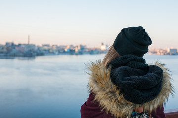 Girl traveler standing on the bridge enjoying view of the city across the river