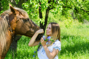 Beautiful girl hugs muzzle of bay peasant horse and laughs