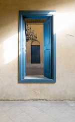 Opened blue wooden window with vintage plaster wall