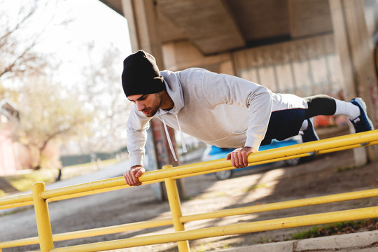 Young Man Doing Push Ups On The Handrail Under The Bridge.