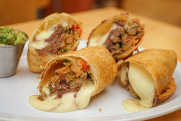 Flour tortilla burrito with beef, avocado and melted cheese, typical Mexican dish.