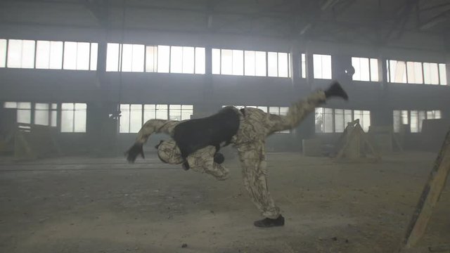 Paintball player in protective uniform and mask aiming gun before shooting. Player gets shot. Violance and war concept.
