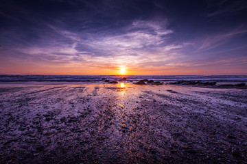 Dramatic sunset with purple sky on the beach at Watergate Bay, Cornwall, England