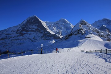 Fototapeta na wymiar Ski slope and snow covered mountains Eiger, Monch and Lauberhorn. Winter day in Grindelwald, Swiss Alps.