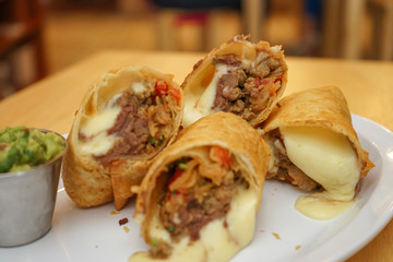 Flour tortilla burrito with beef, avocado and melted cheese, typical Mexican dish.