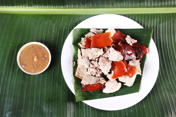 Chopped parts of the delicacy lechon or suckling pig on a banana leaf. The food is popular in Span...