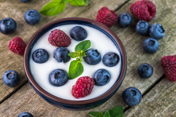 White yogurt with blueberries on the top in blue bowl on natural