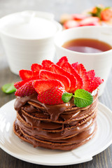 Chocolate pancakes with chocolate cream and strawberries.