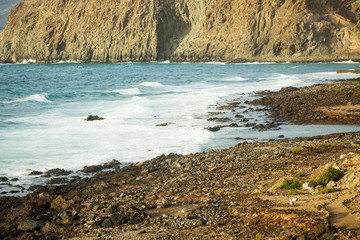 Beautiful blue waves of sea rolling to cliff coast