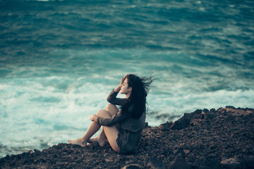 Pretty girl sits on mountain slope