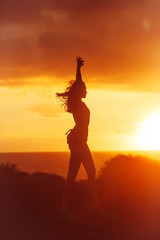 Black silhouette of pretty girl on sea beach at sunset