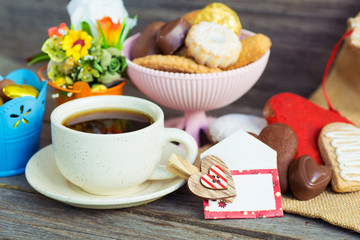 Heart shaped cookies and chocolate candies (big and small as couple), cup of coffee, bouquet of...