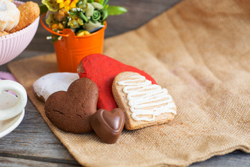 Heart shaped cookies (big and small as couple), cup of coffee, bouquet of flowers decoration. sunny...