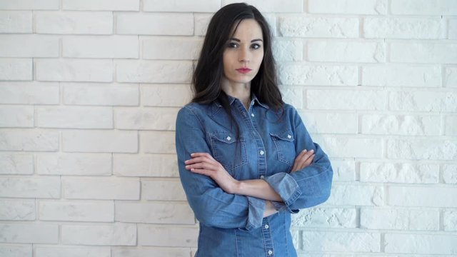 Portrait of serious woman standing by brick wall at home
