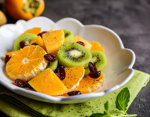 Fruit salad with Minneola tangelo, kiwi, persimmons, cranberries, sprinkled with poppy seeds