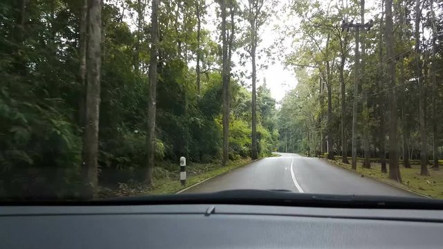 Point of view front driving a car or vehicle on the road in the forest, Thailand, real time