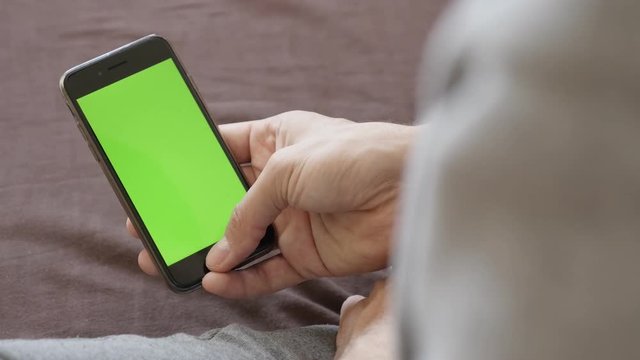 ZAJECAR, SERBIA - JANUARY 2017: Close-up of modern green screen mobile device in man hands at home 