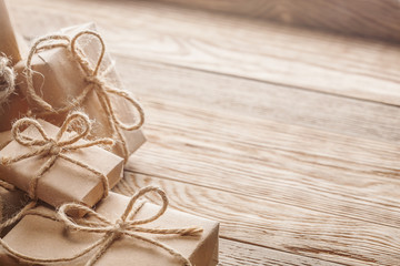 Gift box in kraft paper with bow on wooden background