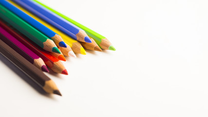 Colored pencils laying on top of each other on a white background
