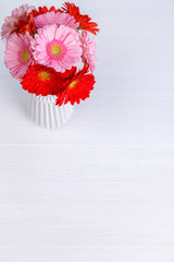 Gerbera flowers in vase on white wood vintage background. 8 march or Valentines day love design. Fresh natural flowers. Painted wooden planks.
