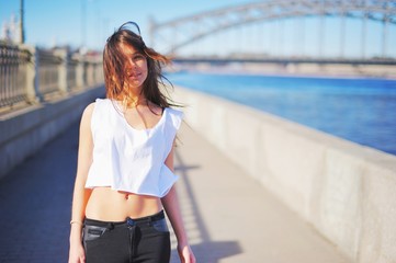 Portrait of young beautiful smiling girl in a short white t-shirt with fluttering on the wind hair...
