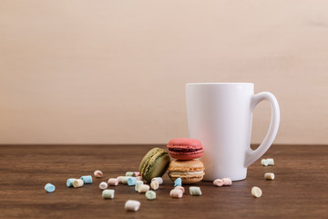 Macaroon cakes with colorful fluffy marshmallows. Mockup white tea cup. Almond sweet cookies. Wooden rustic board.