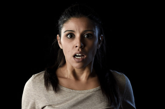 young beautiful scared Spanish woman in shock and surprise face expression isolated on black
