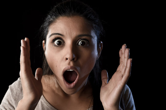 young beautiful scared Spanish woman in shock and surprise face expression isolated on black
