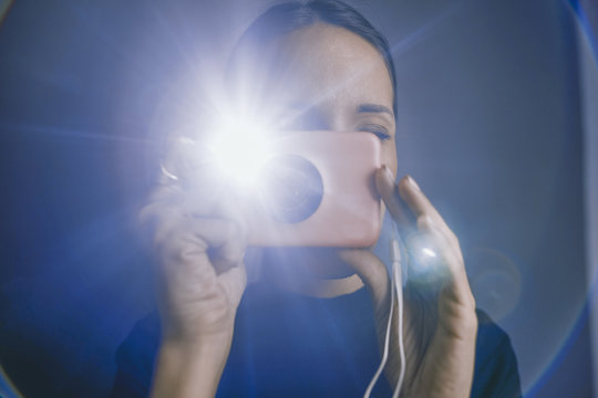 a woman taking a flash picture using an instant film camera