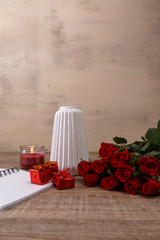Red roses with gift boxes and vase. Valentines day concept. Red pencil with notepad and candle. Love design. Wooden rustic board.