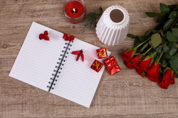 Red roses with gift boxes and vase. Valentines day concept. Red pencil with notepad and candle. Love design. Wooden rustic board.
