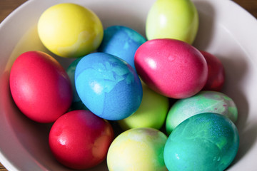 Easter multycoloured painted numerouse eggs lying in a white plate
