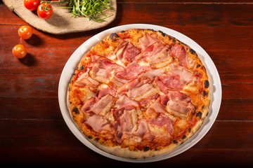 Pizza with mozzarella cheese and ham on a plate